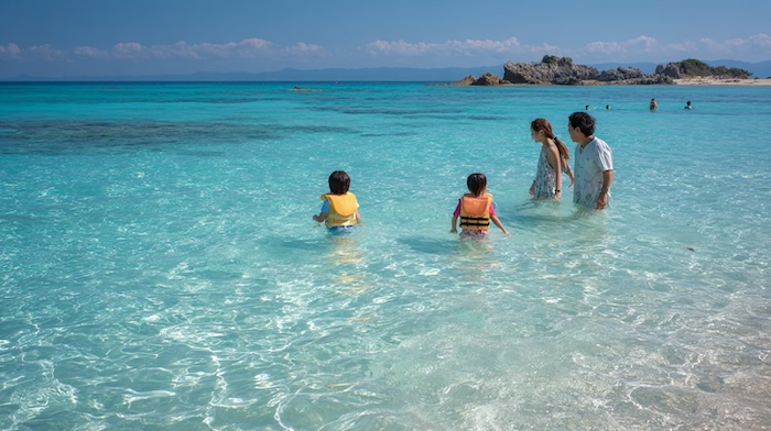 沖縄の海で遊んでいる家族